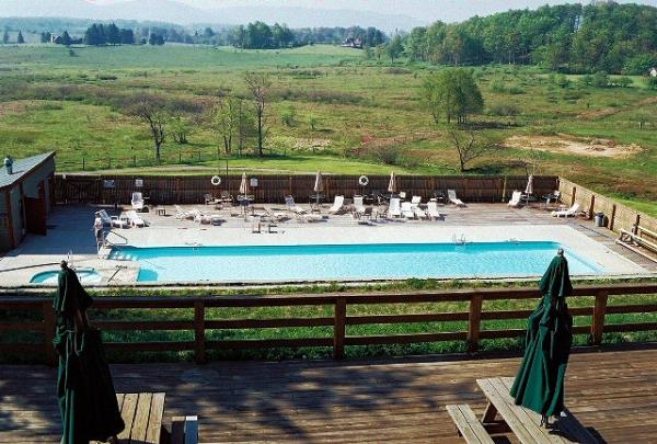 Large swimming pool and toddler behind lodge
