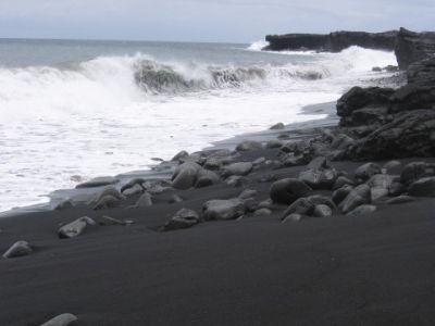 Surf breaking on black sand beach in Hawaii